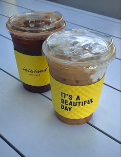 two cups of iced coffee sitting on top of a wooden table next to each other