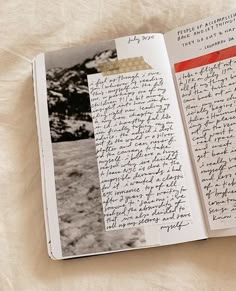 an open book with writing on it sitting on top of a white sheeted surface