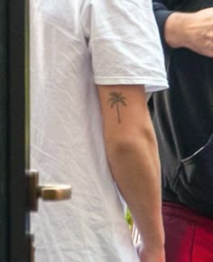 a man with a small palm tree tattoo on his left arm, and red shorts