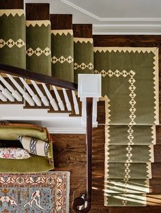 the stairs are lined with green rugs and decorative wall hangings, along with an area rug