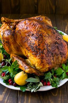 a roasted turkey on a platter with cranberries, lemons and parsley