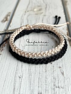 three braided bracelets sitting on top of a white wooden table next to two knitting needles