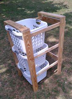 three white laundry baskets stacked on top of each other next to a wooden rack in the grass