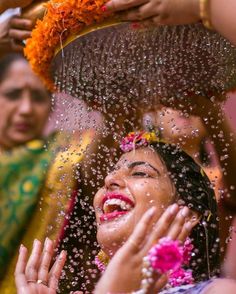 a group of people standing around each other with water on their head and hands in the air