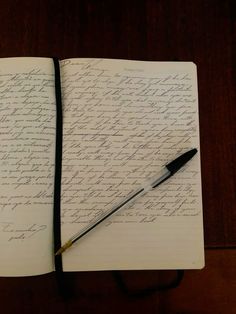 an open notebook with writing on it and a pen resting on the page next to it