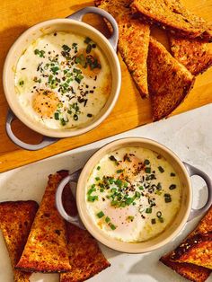 two bowls filled with soup next to some pita chips