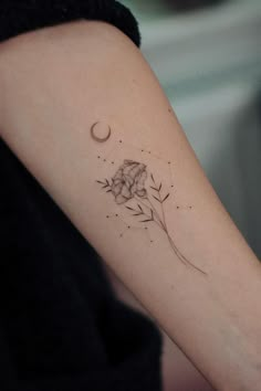 a woman's arm with a flower and crescent moon tattoo on the left inner arm