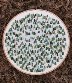 a cross stitch pattern with pine trees in the middle and green leaves on the bottom