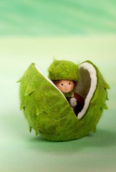 a small doll in a green ball with leaves