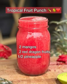 a jar filled with red dragon fruit on top of a wooden cutting board next to a knife