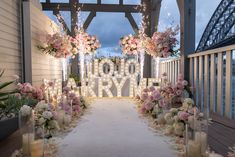 an outdoor wedding setup with flowers and candles on the aisle, surrounded by lit up letters