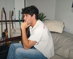 a young man sitting on top of a couch next to guitar strings in a living room