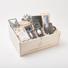 a wooden box filled with assorted items on top of a white table next to a vase