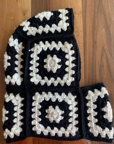 a black and white crocheted dishcloth on top of a wooden floor next to a pair of oven mitts