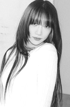 a black and white photo of a woman with long hair, wearing a white shirt