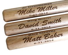 three wooden baseball bats with names and date engraved on them sitting on a carpeted surface