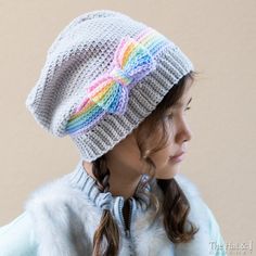 a woman wearing a knitted hat with a rainbow bow on the front and side