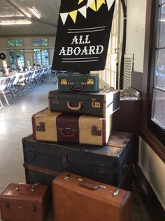 several suitcases stacked on top of each other in front of a sign that says all aboard