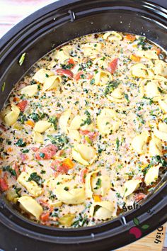 a crock pot filled with tortellini shells covered in cheese and seasoning