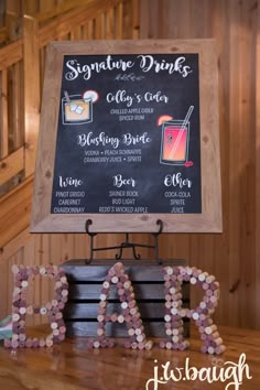 a sign that says signature drinks on top of a wooden table with wine glasses in the shape of letters