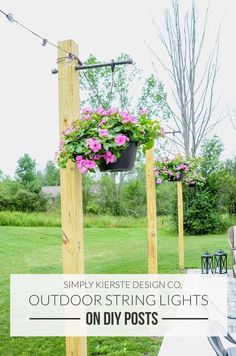 hanging planters filled with pink flowers on wooden poles