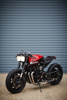 a red and black motorcycle parked in front of a garage door