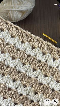 a crocheted blanket sitting on top of a table next to a ball of yarn