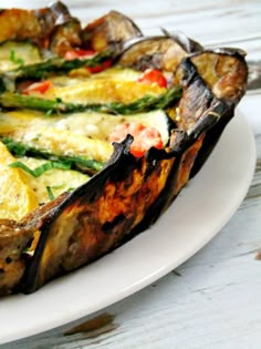 an egg dish with asparagus and tomatoes on a white plate