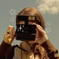 a woman holding up a camera to take a picture with the sky in the background