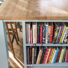 a book shelf filled with books on top of a wooden floor next to a table