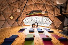 a person doing yoga in a large room with wooden flooring and walls that have round windows