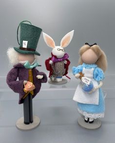 three small figurines are standing next to each other wearing hats and dresses,