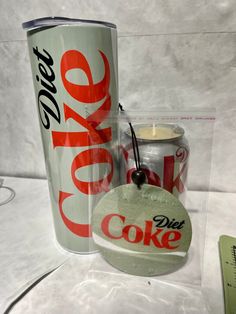 a coca cola can next to a candle with a tag on it and another item in the background