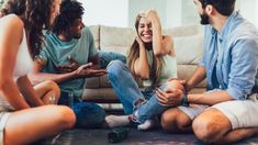 a group of people sitting on the floor talking to each other and laughing at one another