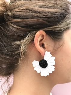 a close up of a person wearing earrings with flowers on the back of their ears