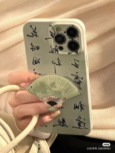 a woman holding a cell phone case with chinese writing on it and a fan in her hand