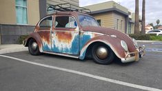 an old rusted out car is parked in a parking lot next to a building