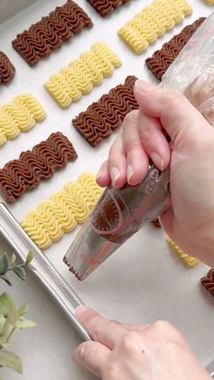 someone is decorating some cookies with icing and chocolate on a tray next to flowers