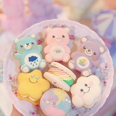 there are many small teddy bears in the cupcakes on the plate, and one is holding it up