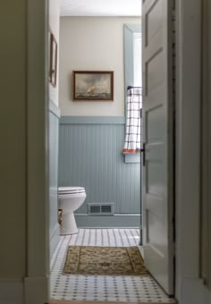 an open door leading to a bathroom with a toilet and rug on the floor in front of it