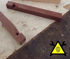 two pieces of wood sitting on top of a wooden floor next to a ruler and pencil