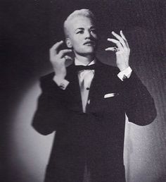 a man in a tuxedo is holding his hand up to the side with one hand