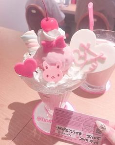 there is a small ice cream sundae with pink decorations on it and a person holding up a card