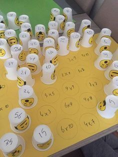 a yellow table topped with lots of cups filled with emotictive faces and numbers