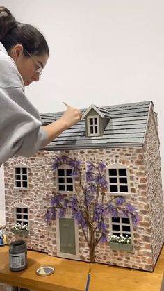 a woman standing next to a model house