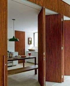 an open door leading to a kitchen and dining room with wood paneling on the walls