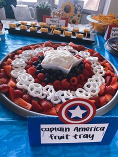 a captain america fruit tray is displayed on a table with other foods and desserts