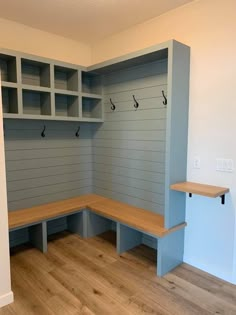 an empty room with benches and shelves on the wall, in front of a wooden floor