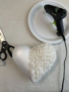 a pair of scissors and a white heart on a plate with some glue attached to it