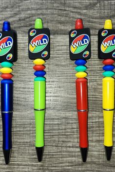 three different colored pens sitting next to each other on top of a wooden table,